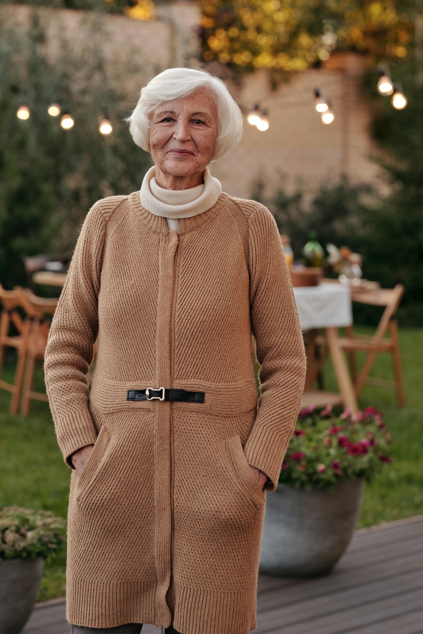 Cheerful senior woman in a cozy cardigan enjoying an outdoor gathering in the garden.